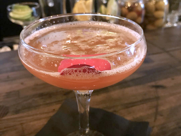 pink colored cocktail with flower petal 