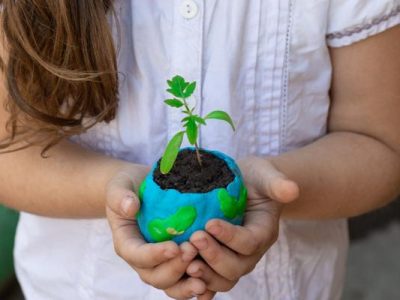 close up of little girl holding an plant in a earth shaped planter