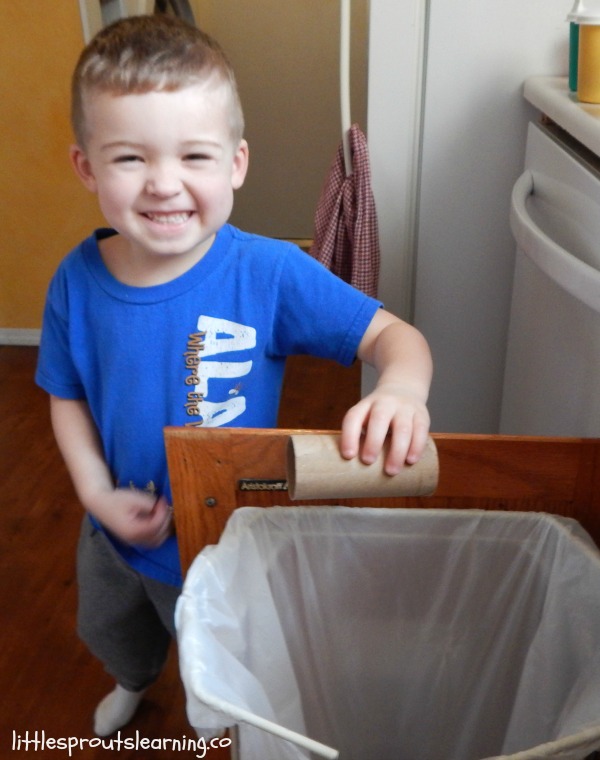 small boy in blue shirt putting cardboard tube in recycling