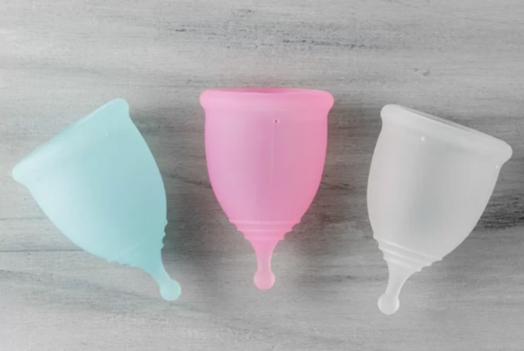 three menstrual cups on grey table