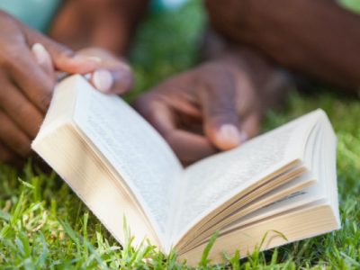 people laying in grass reading with text 20 earth day books for kids